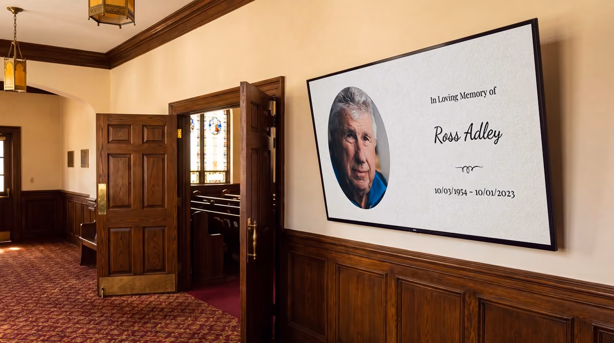 A title slide on a screen in a chapel entrance, reading In Loving Memory of Ross Adley