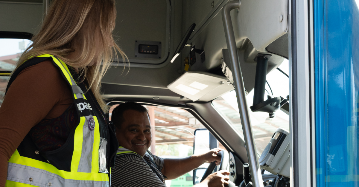 A driver smiles while seated in a Santa Clarita Transit vehicle as a Spare team member looks on capturing the hands-on training and collaboration that supported the launch.