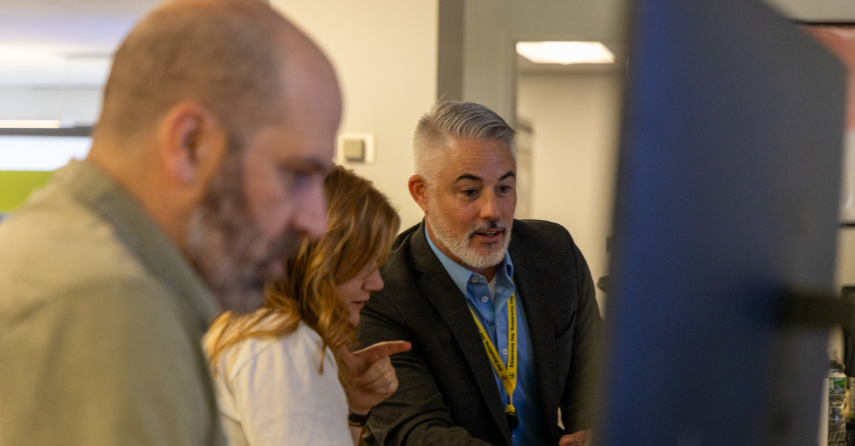 MBTA and Spare's Chad Ballentine collaborate closely at a computer, reviewing system updates during The RIDE rollout.
