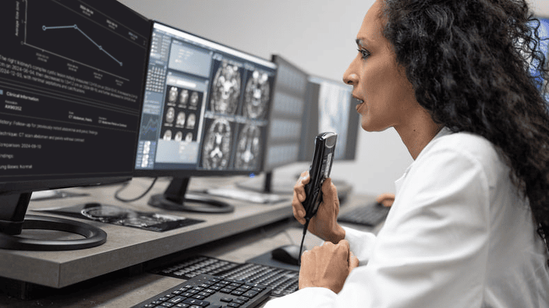 Radiologist reviewing brain scans and using dictation tools for reporting.