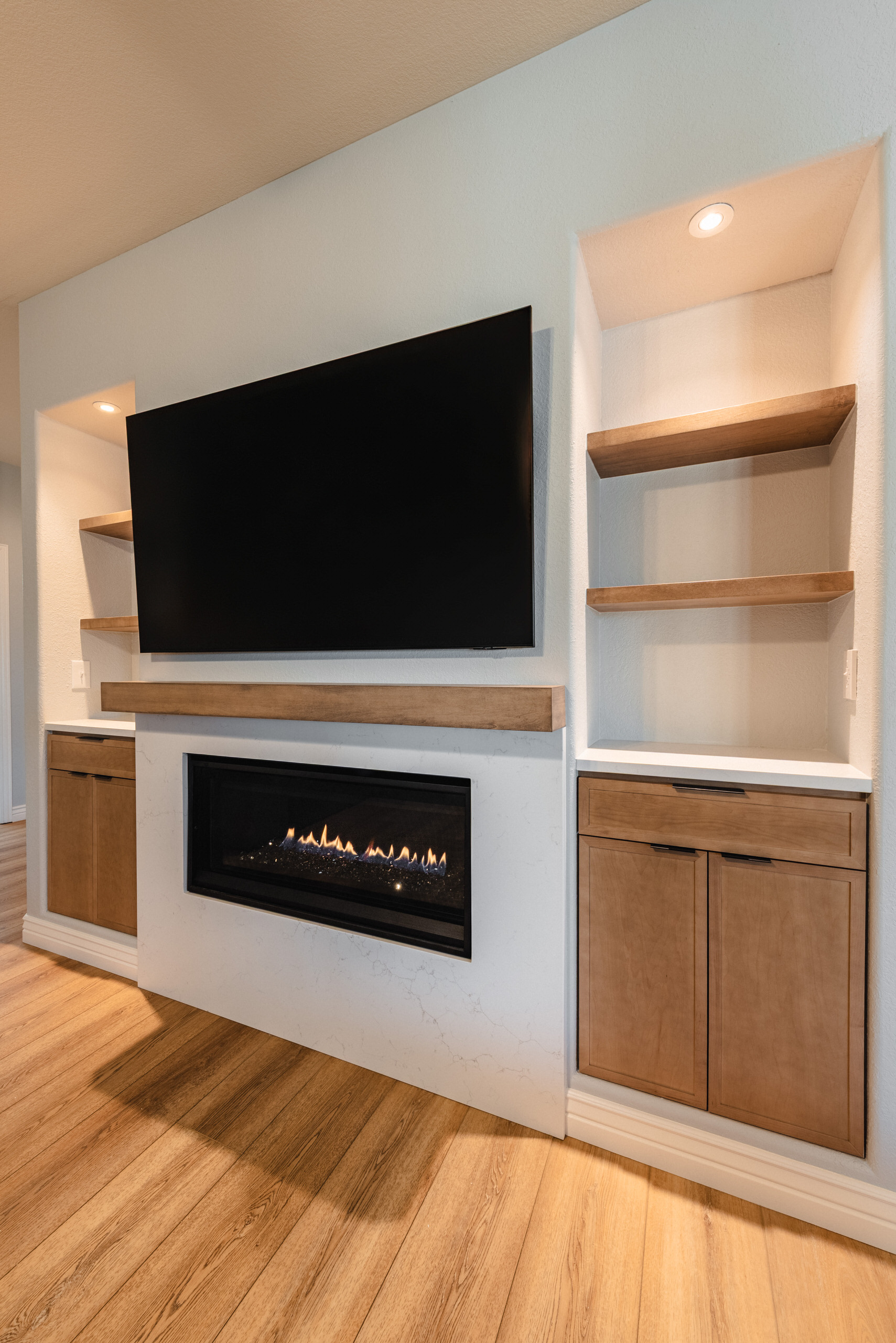 Angled perspective of the white quartz fireplace surround showing the seamless integration with the custom-built shelving unit.