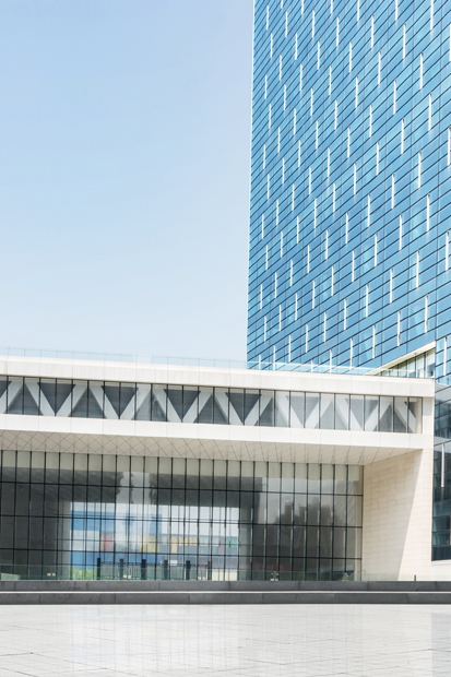 Glass office tower beside a low stone building