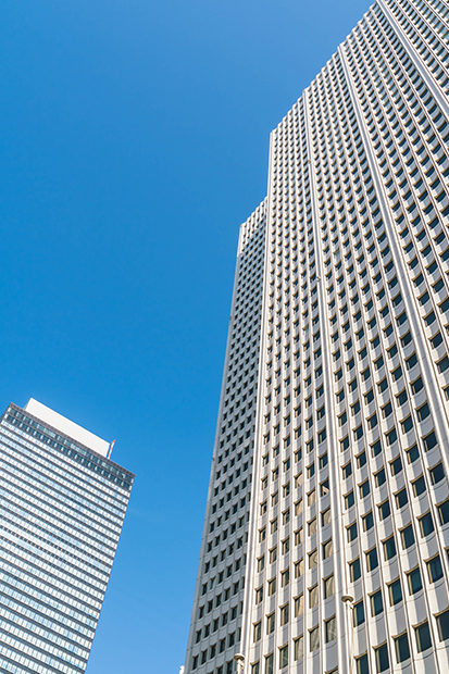 Looking up at two glass towers against a clear blue sky