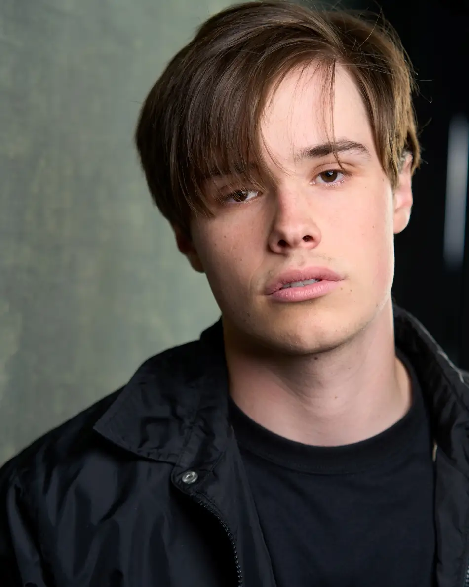 Atlanta men’s actor headshot — young male with brown hair and brooding expression in black jacket, edgy theatrical look for loner, stoner, or outsider roles in teen and young adult dramas.