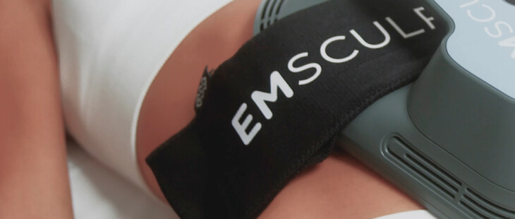 A woman getting emsculpt treatment at a salon