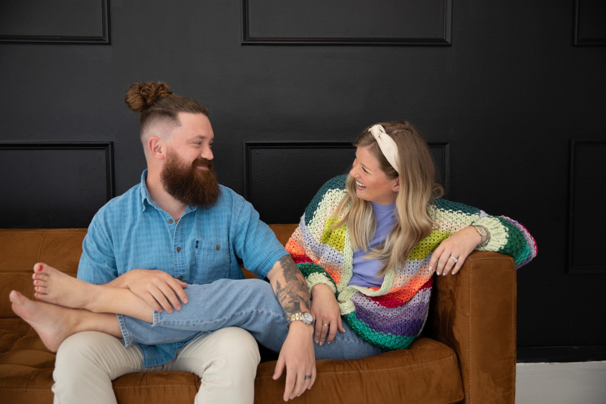 Cody and Jordan smiling at each other on a couch