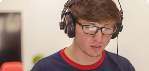 Young man wearing glasses and headphones, looking down with a focused expression.