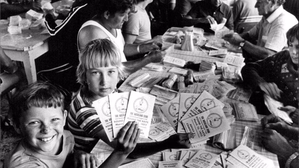 An old black and white photo of smiling children preparing race programmes 