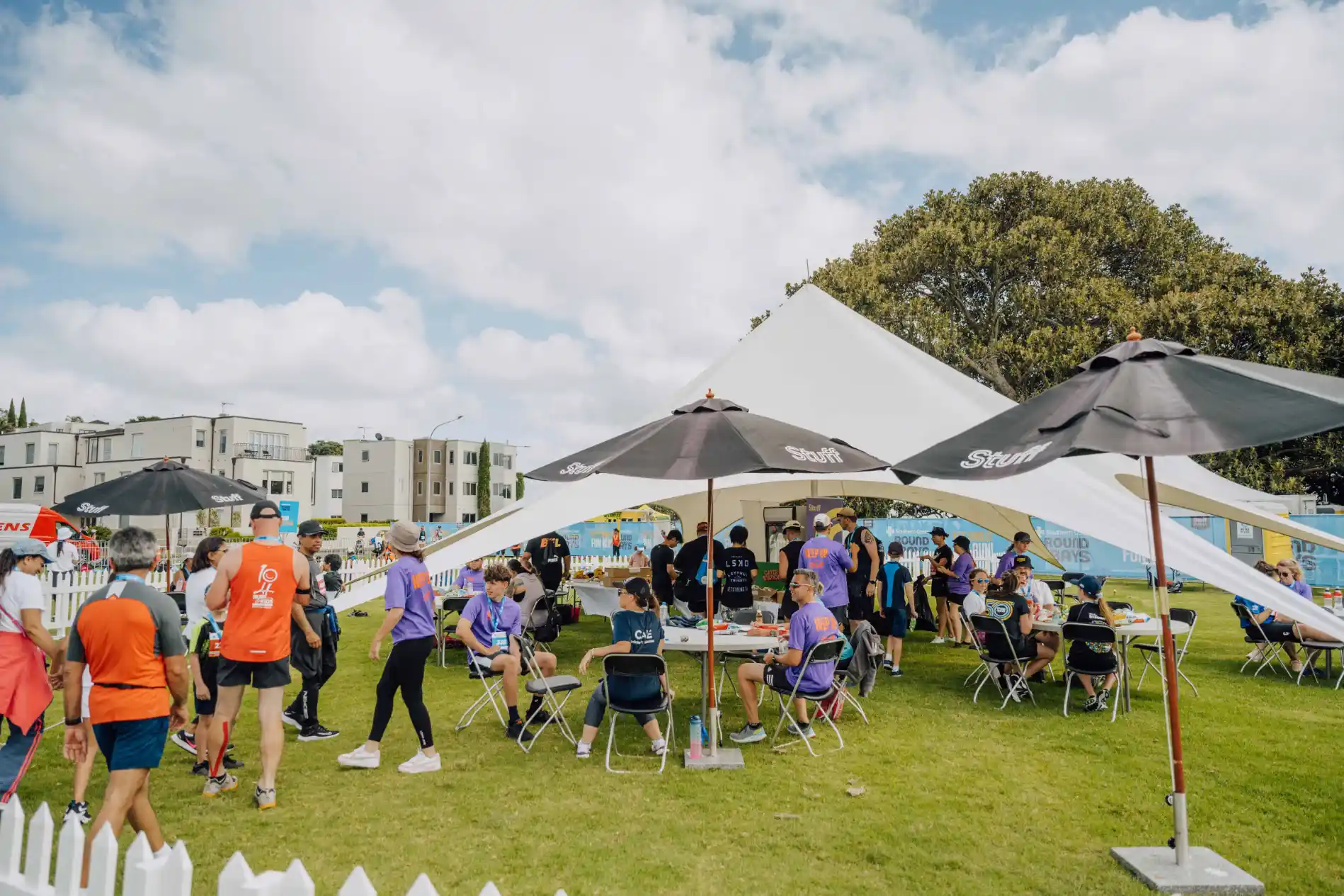 A group of people in active wear sit around shaded tables