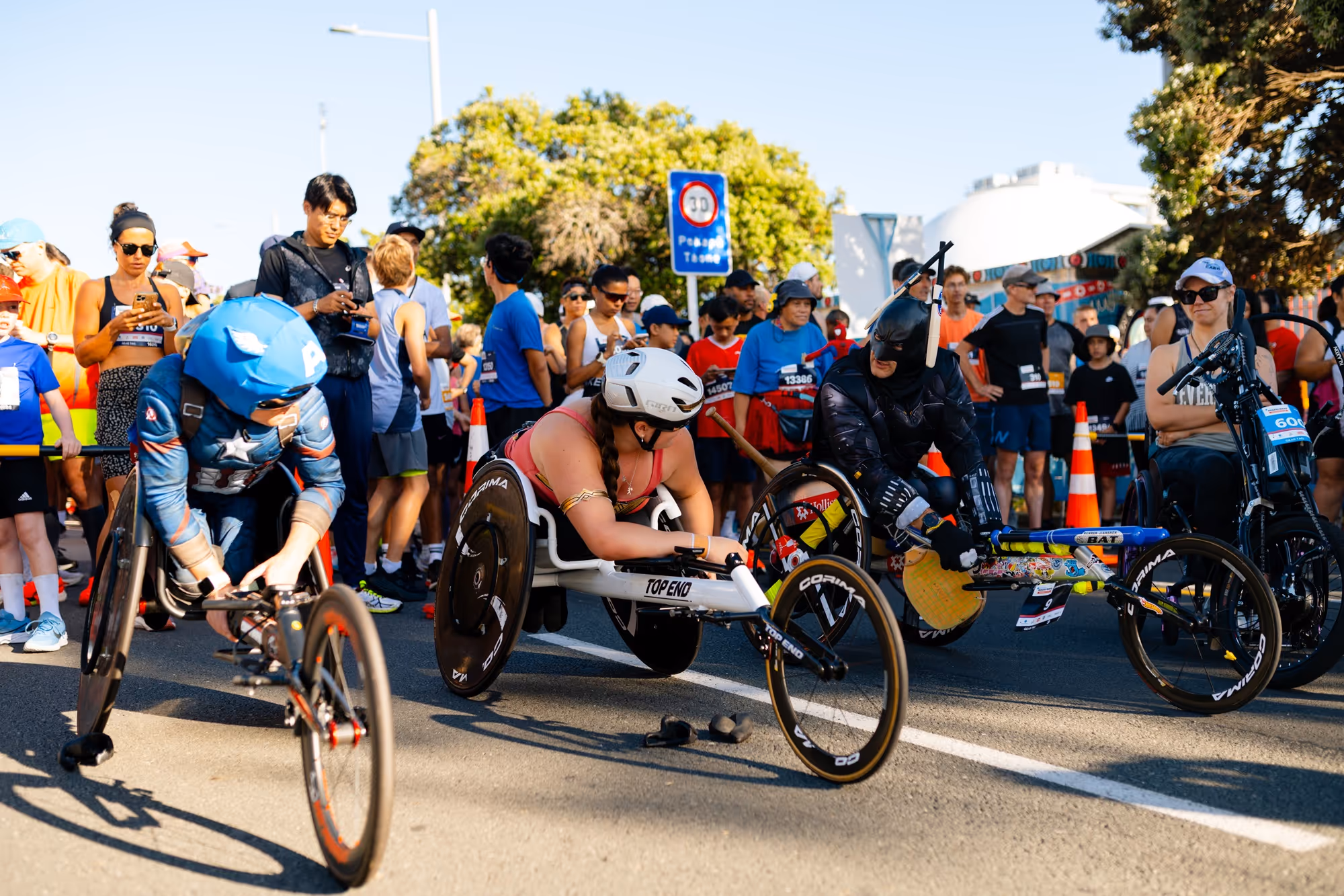 A man in a fancy dress costume wins a wheelchair race. He's got a big smile on his face
