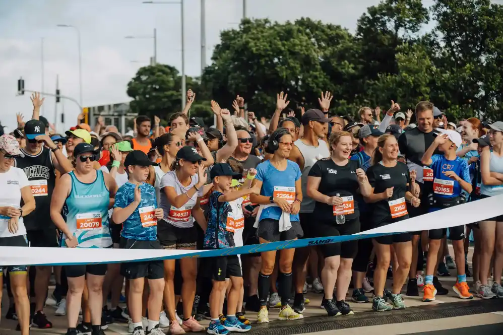 A wheelchair racer dressed in fancy dress smiles as he crosses the line at a race