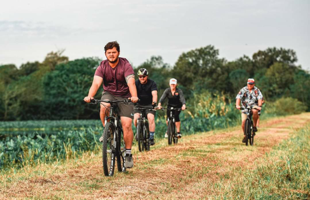 Four people bike riding on a trail through Cattail Marsh.