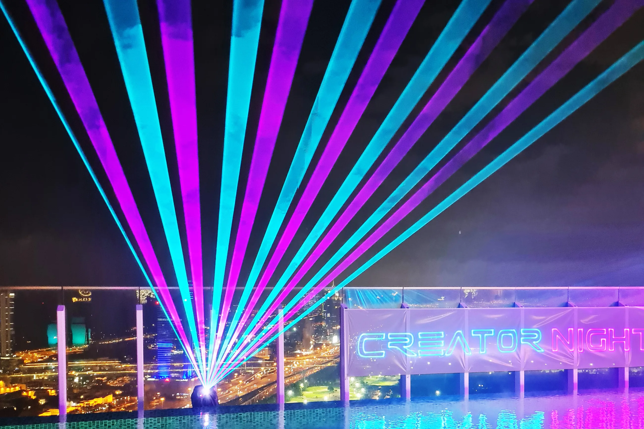 Laser fans rising over the rooftop pool with Creator Night written in laser, Dubai, UAE