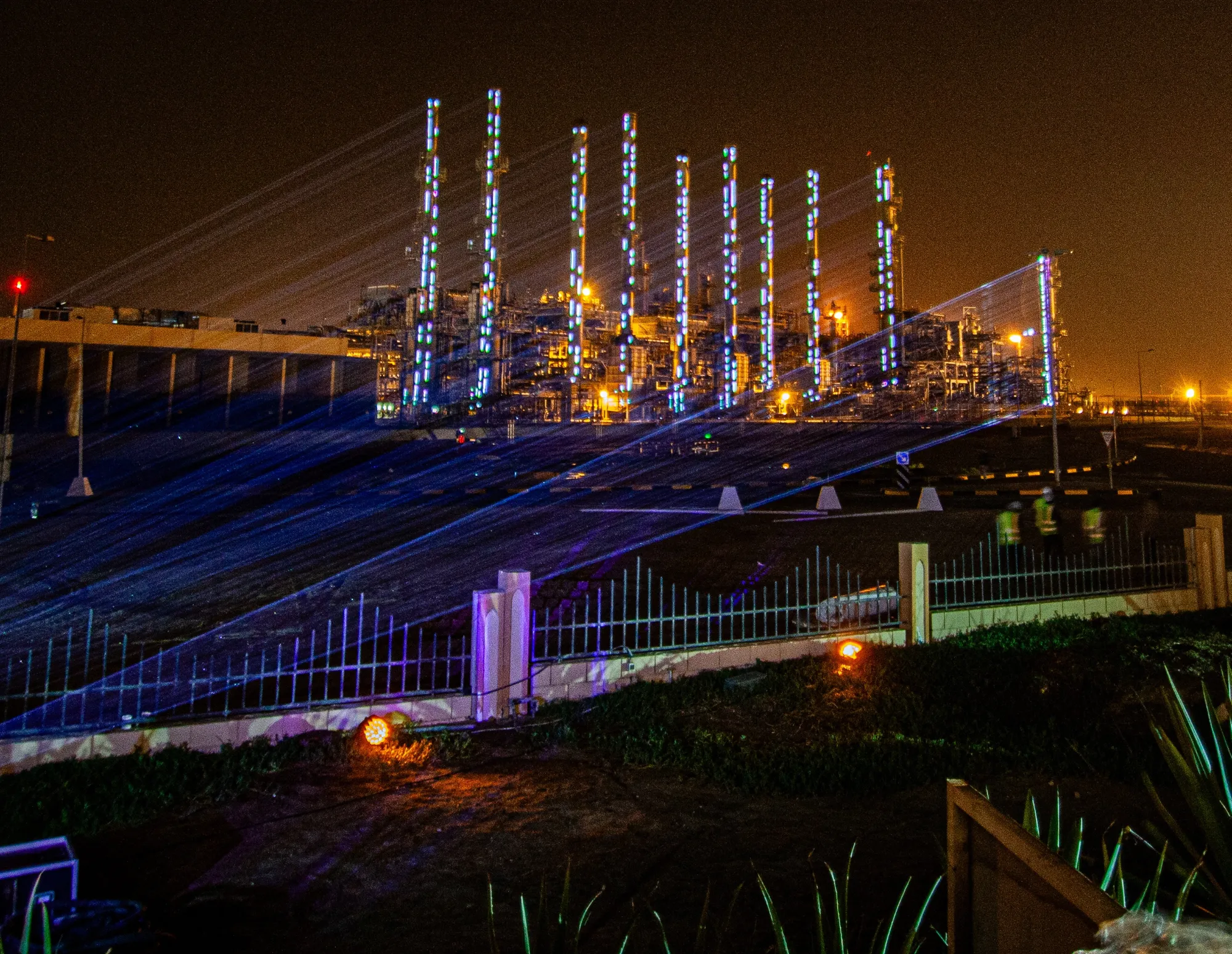 Blue lasers mapping the gas plant towers at night, BANAGAS Multimedia Show, Bahrain