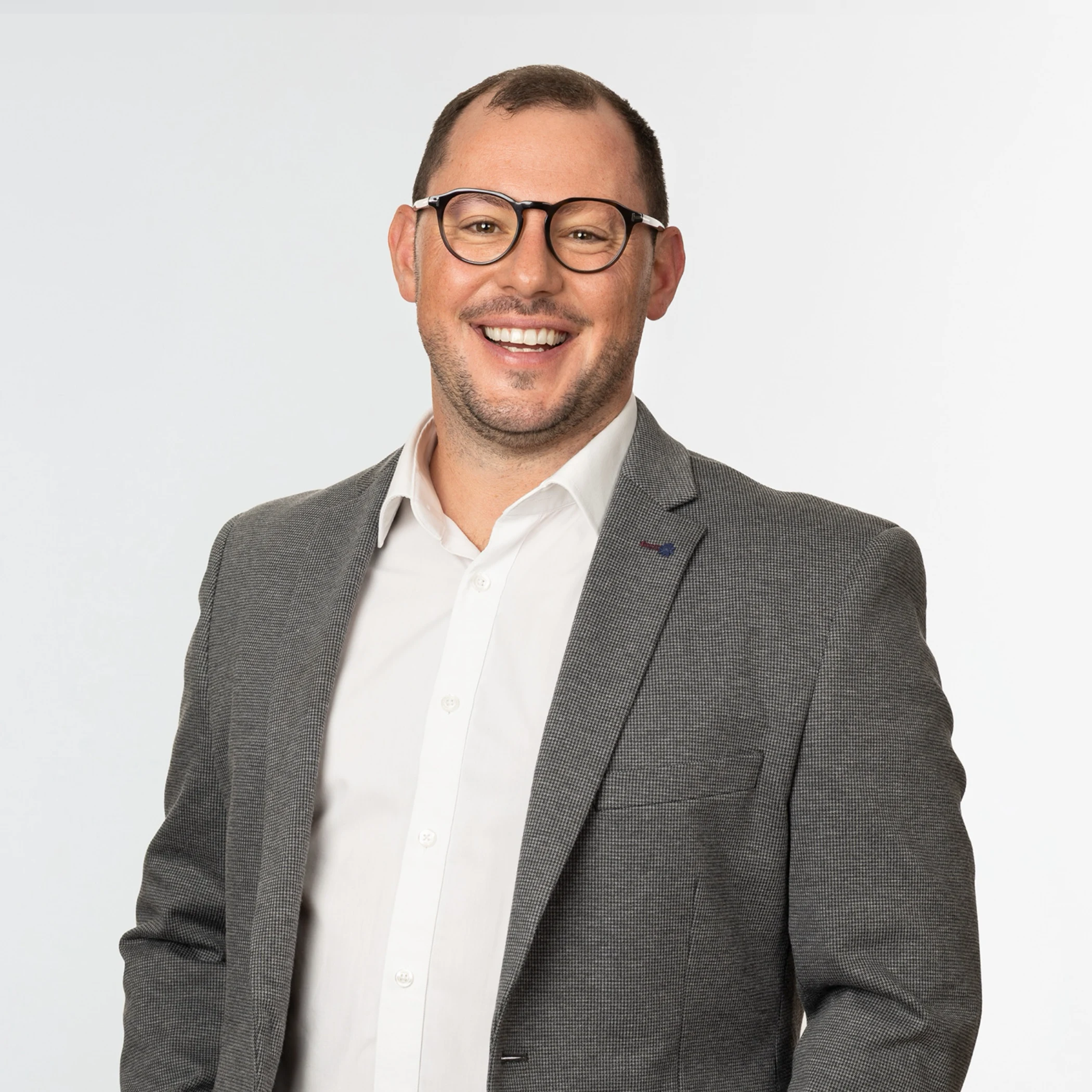 A man in a suit and glasses smiling