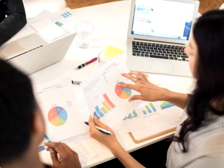 Two ethnic businesswomen reviewing charts and graphs.