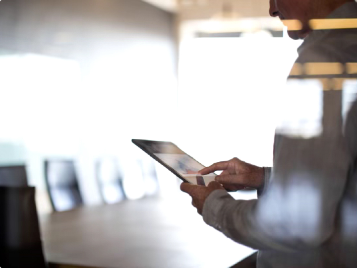 Older businessman working on digital tablet in empty conference room.