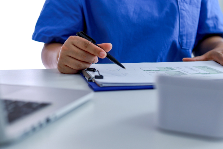 Male physician looking at a binder clipboard of medical documentation.