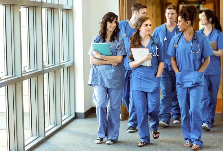Group of young doctors walking down hospital hallway.