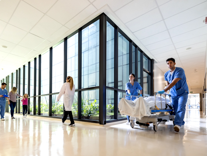 Emergency medical staff wheeling patient on a gurney down the hospital hallway.