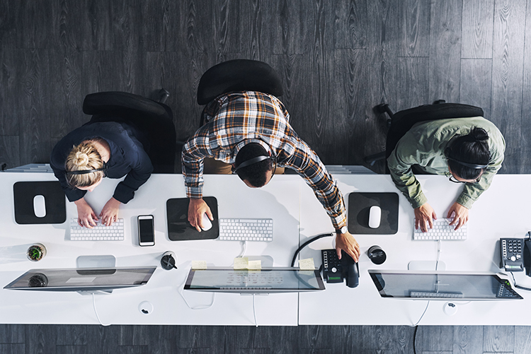 Picture of three call center employees working with headsets and computers.