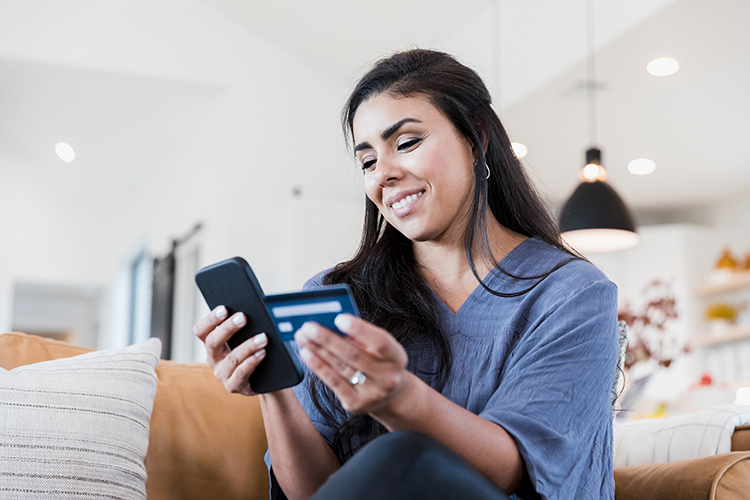 Ethnic female patient making a mobile payment on mobile phone using a credit card.
