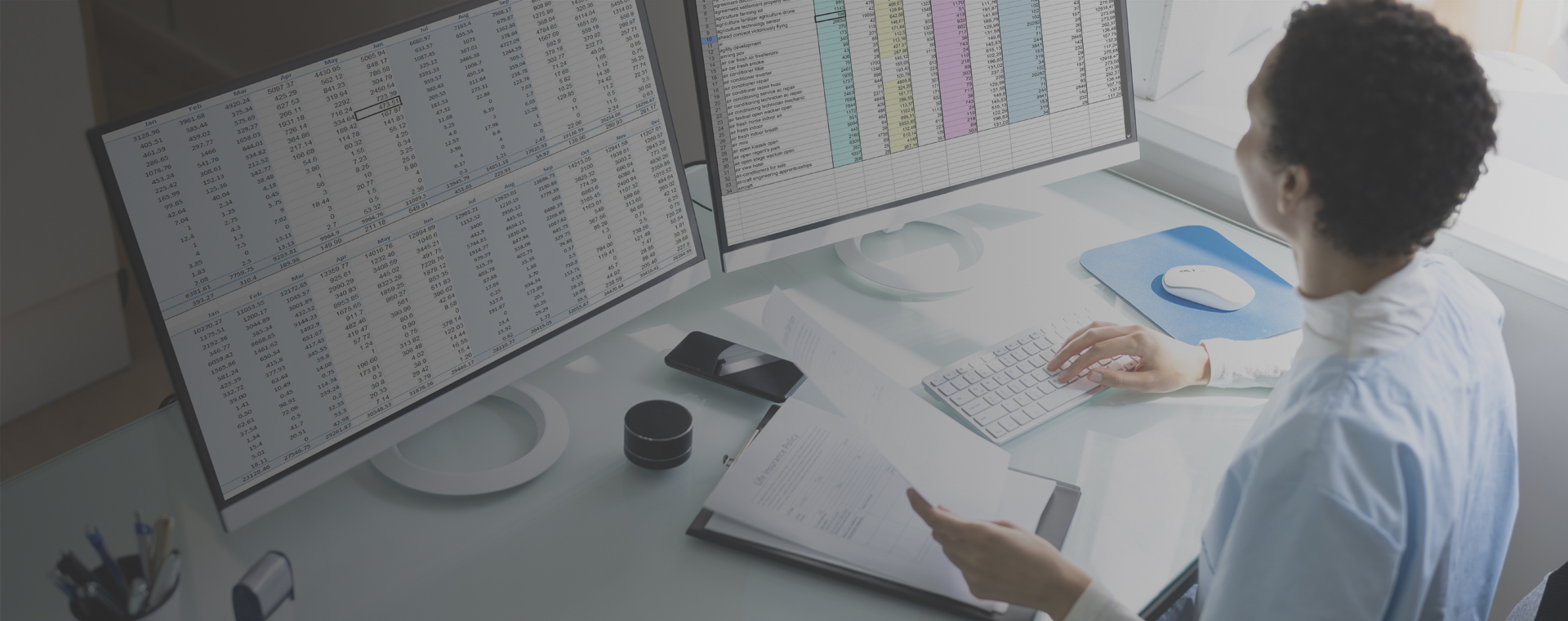 Ethnic businesswoman performing coding and billing operations on double monitors.