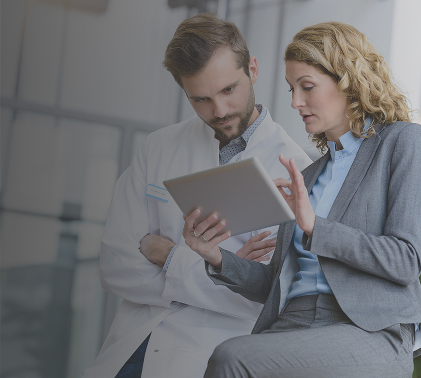 A businesswoman showing a male physician content on her digital tablet.