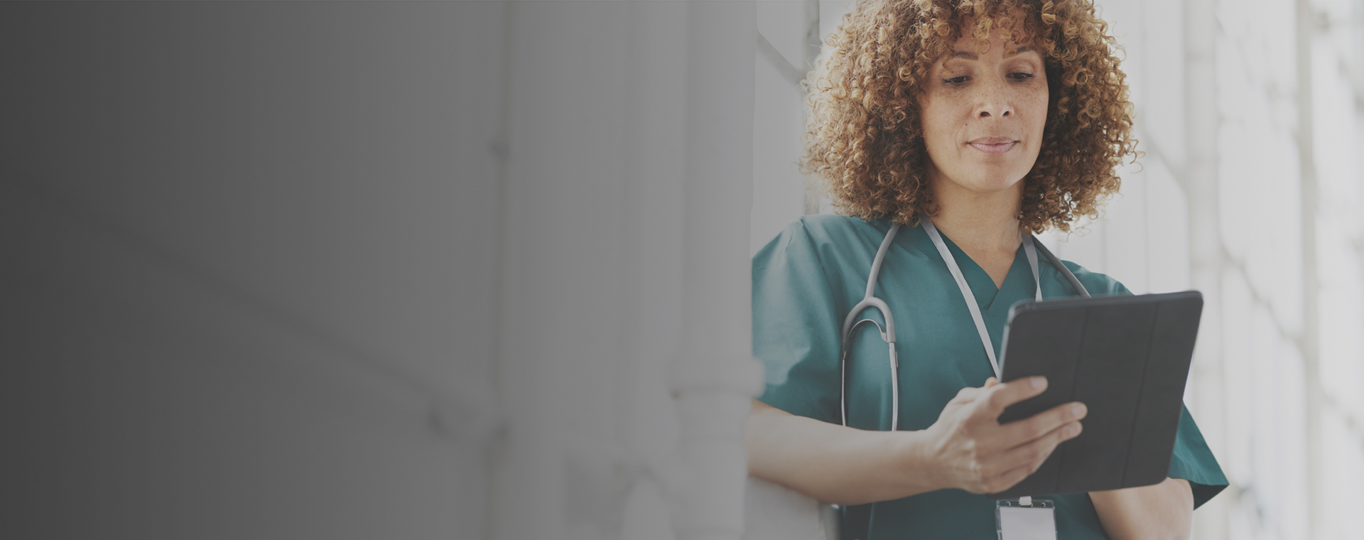 A biracial female physician looking at her digital tablet.