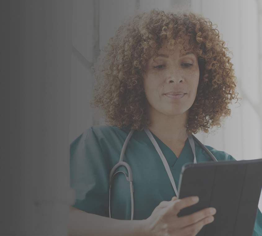 A biracial female physician looking at her digital tablet.
