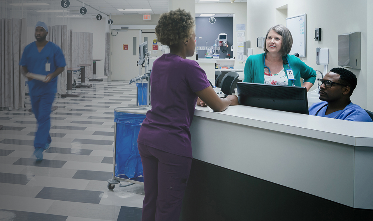 Multi-ethnic medical staff talking at emergency room desk.