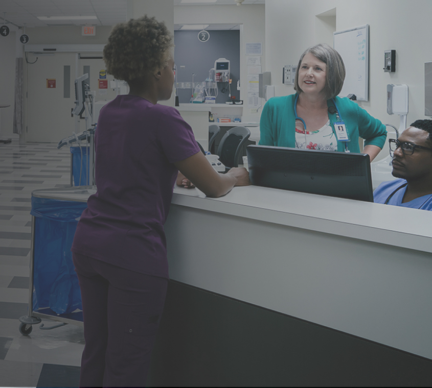 Multi-ethnic medical staff talking at emergency room desk.