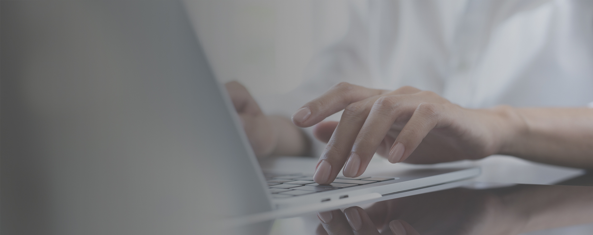 A woman's fingers typing on a laptop keyboard.