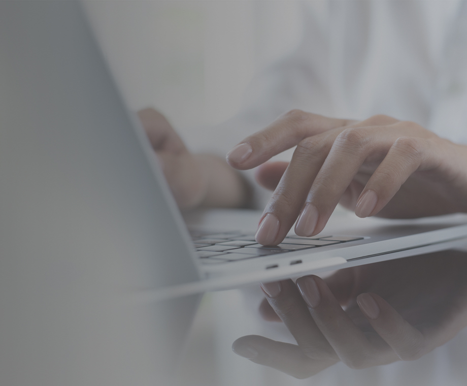 A woman's fingers typing on a laptop keyboard.