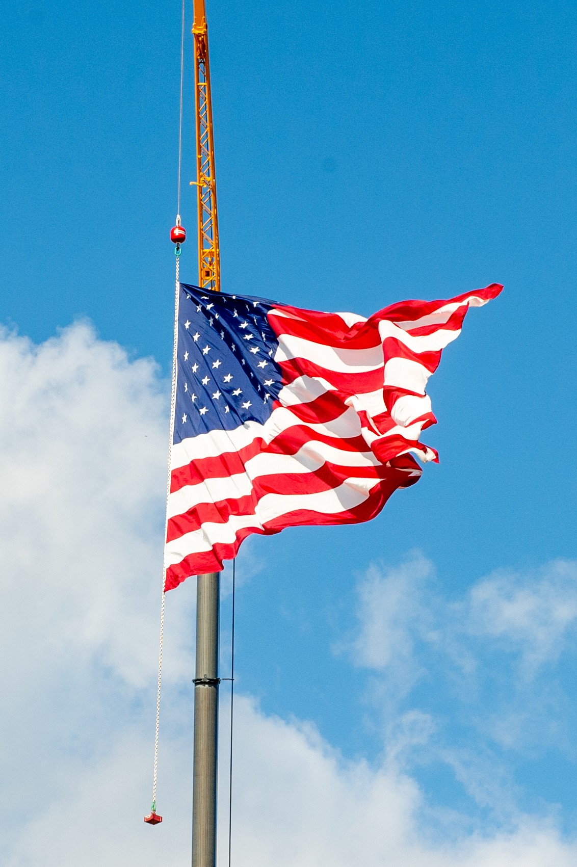 A photo of an American flag held aloft by a crane.