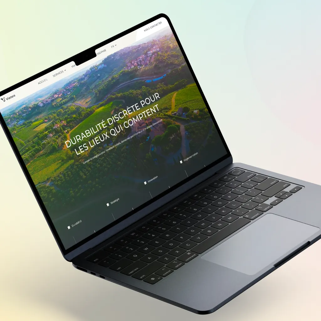 Ordinateur portable affichant la page web Viatera avec une vue aérienne de paysage rural et texte en français sur la durabilité discrète.