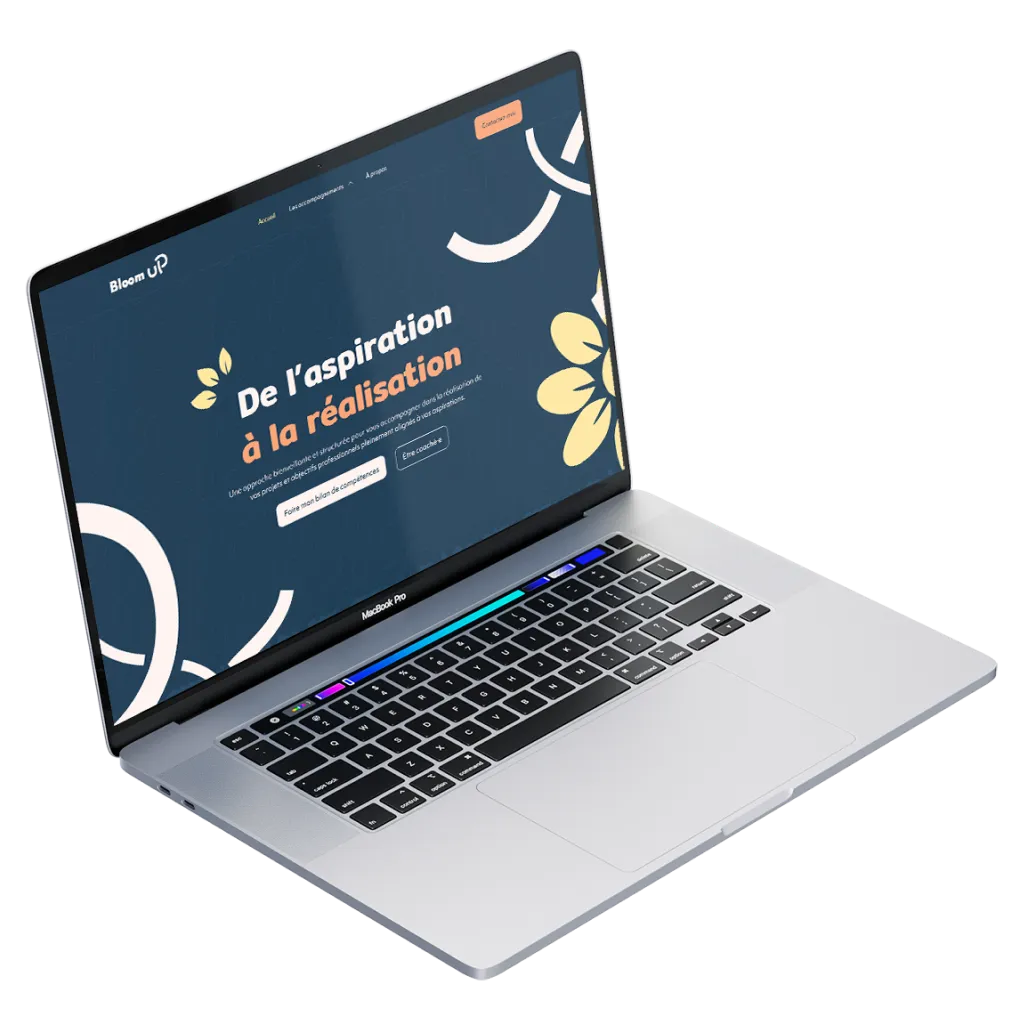 Ordinateur portable MacBook Pro affichant un site web avec le texte principal « De lâaspiration Ă la rĂ©alisation » sur fond bleu avec des Ă©lĂ©ments graphiques floraux jaunes et blancs.
