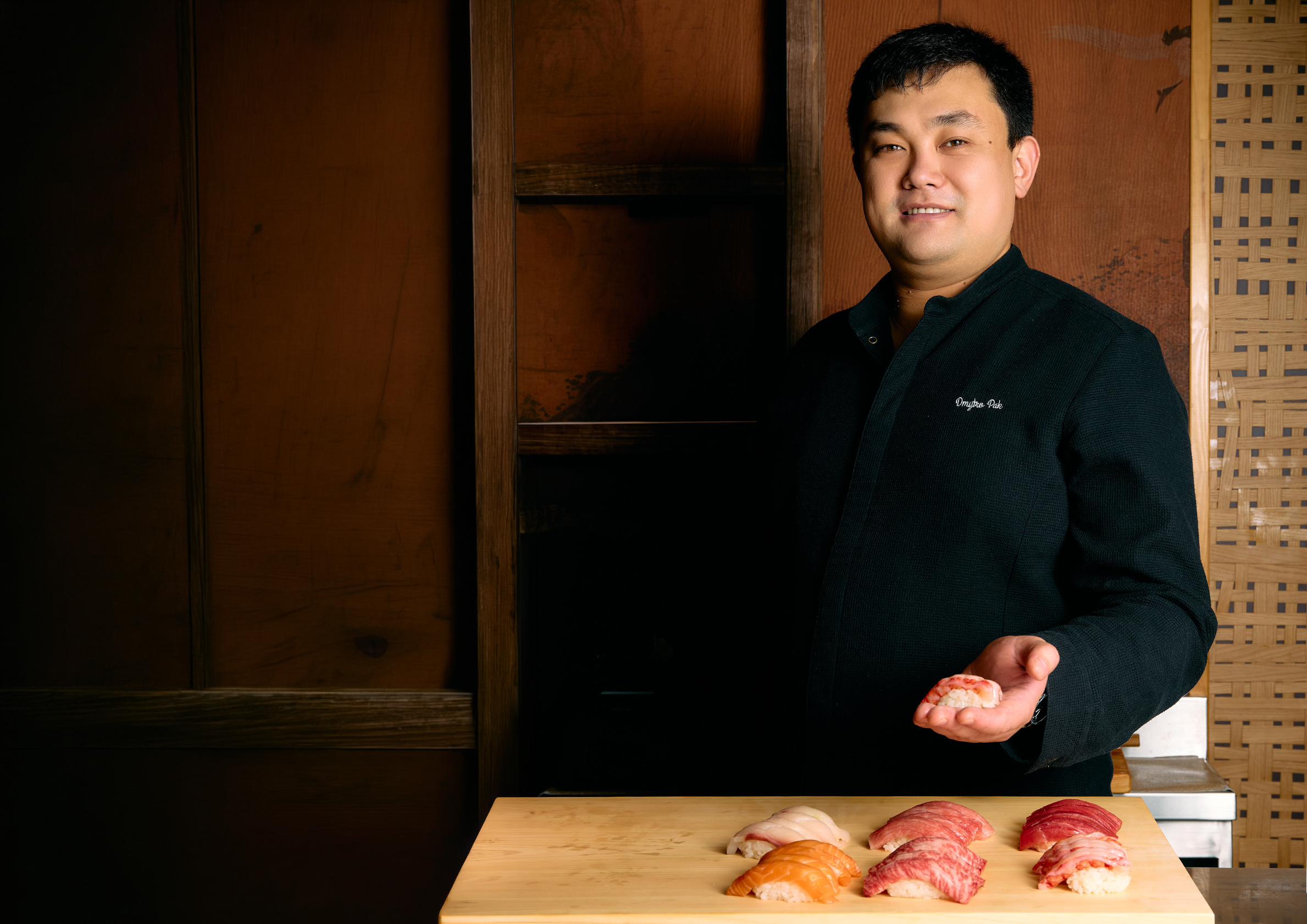 Chef Dmytro Pak holding nigiri at the Omakase counter