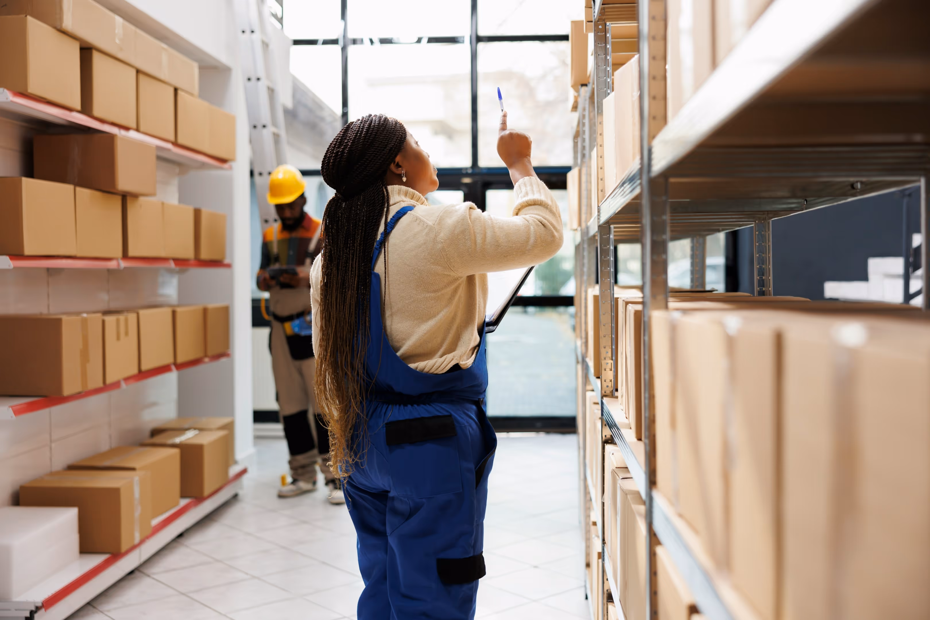A woman taking inventory of boxes on shelving.