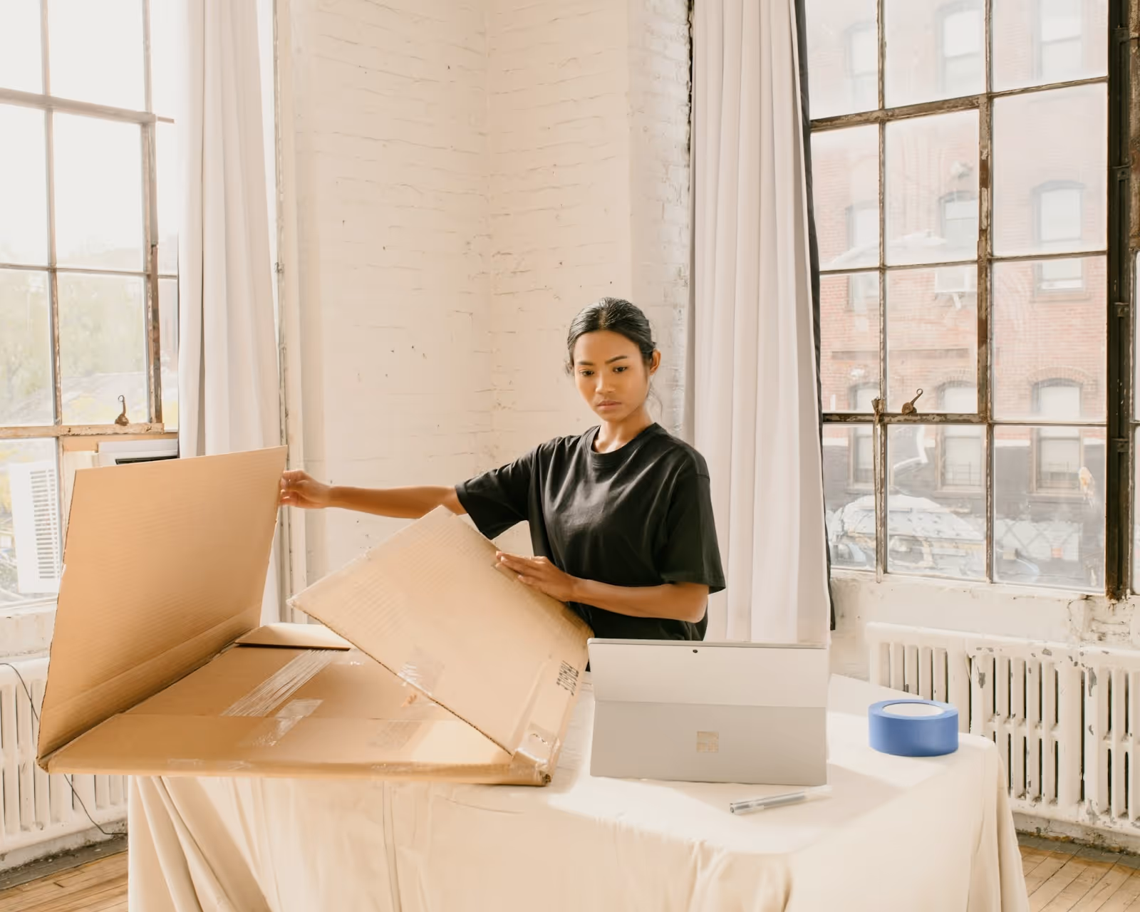A woman in a bright loft prepping a box for shipping.