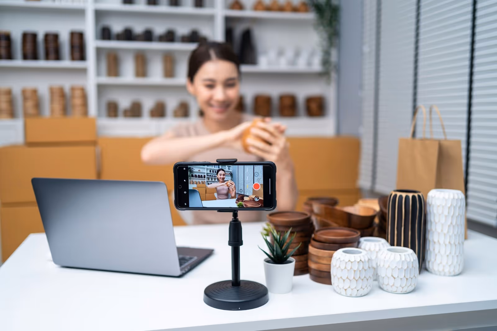 A woman behind a phone recording herself for social media, talking about her products.