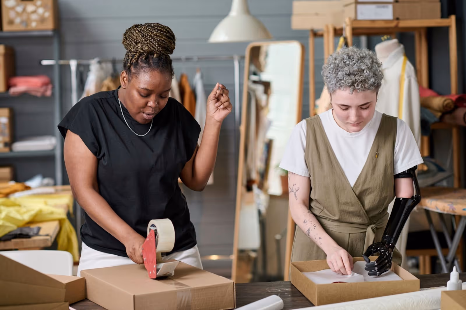 Two women standing at a table packing online customer orders.