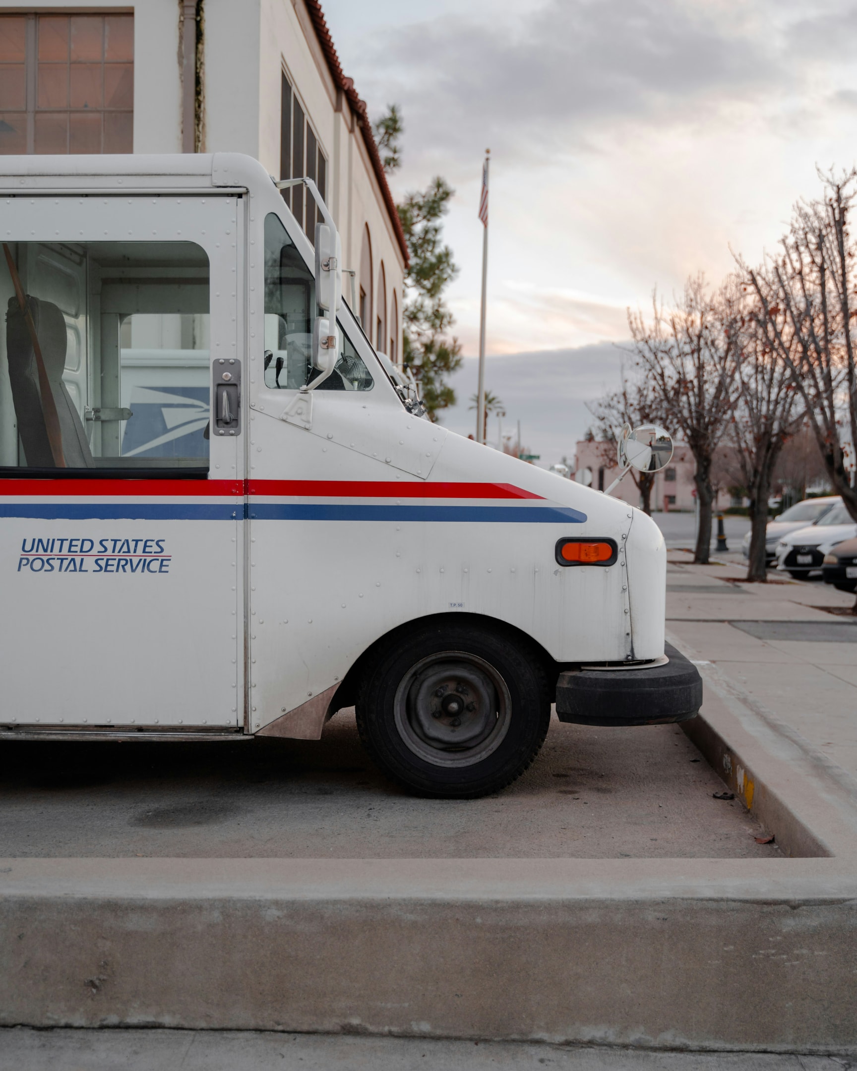 A USPS delivery truck parked outside the post office, preparing for the busy holiday season. This scene highlights the importance of shipping deadlines, as customers aim to send holiday gifts on time using services like priority mail and USPS ground advantage.