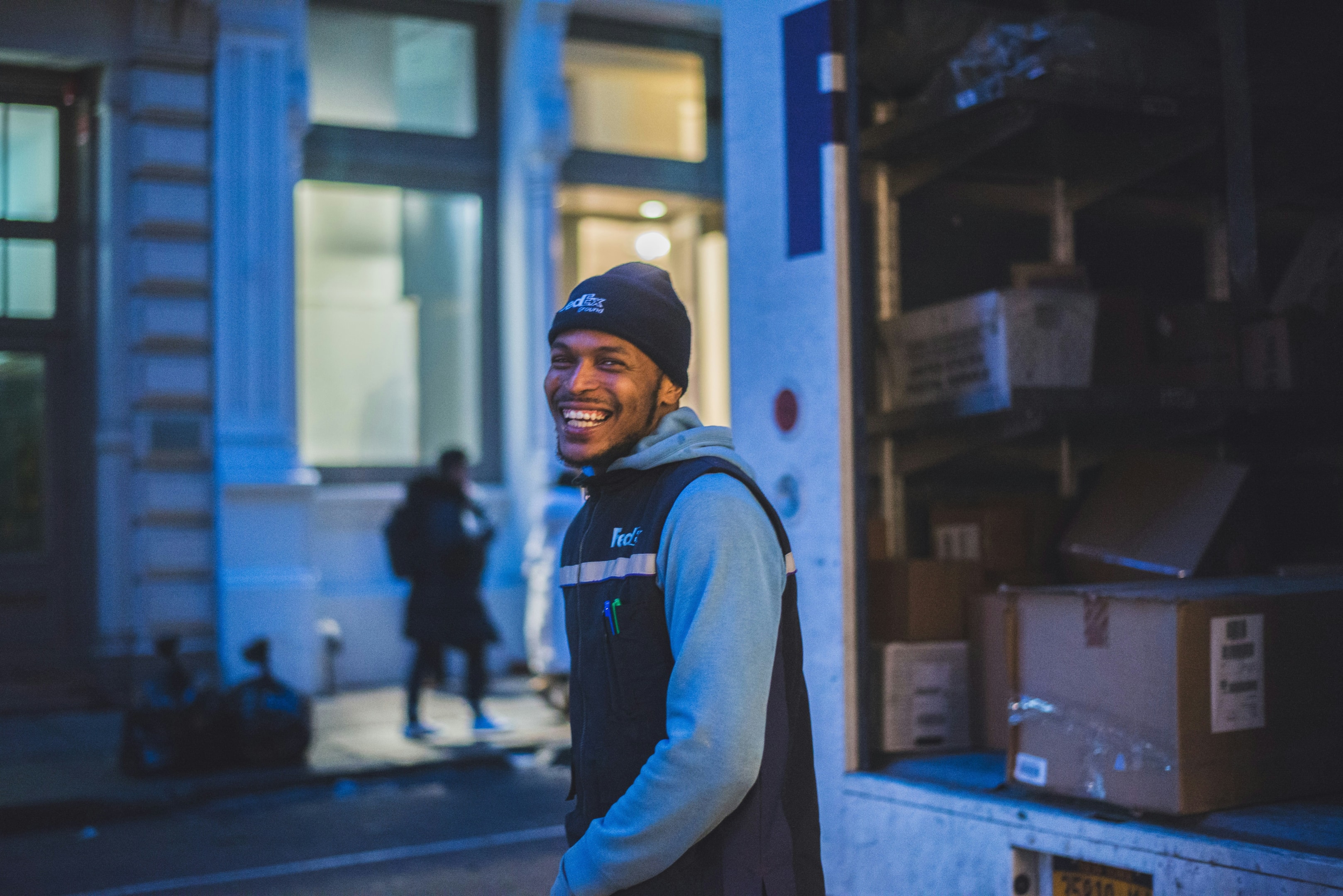 A FedEx delivery driver smiling while unloading packages froom a truck.