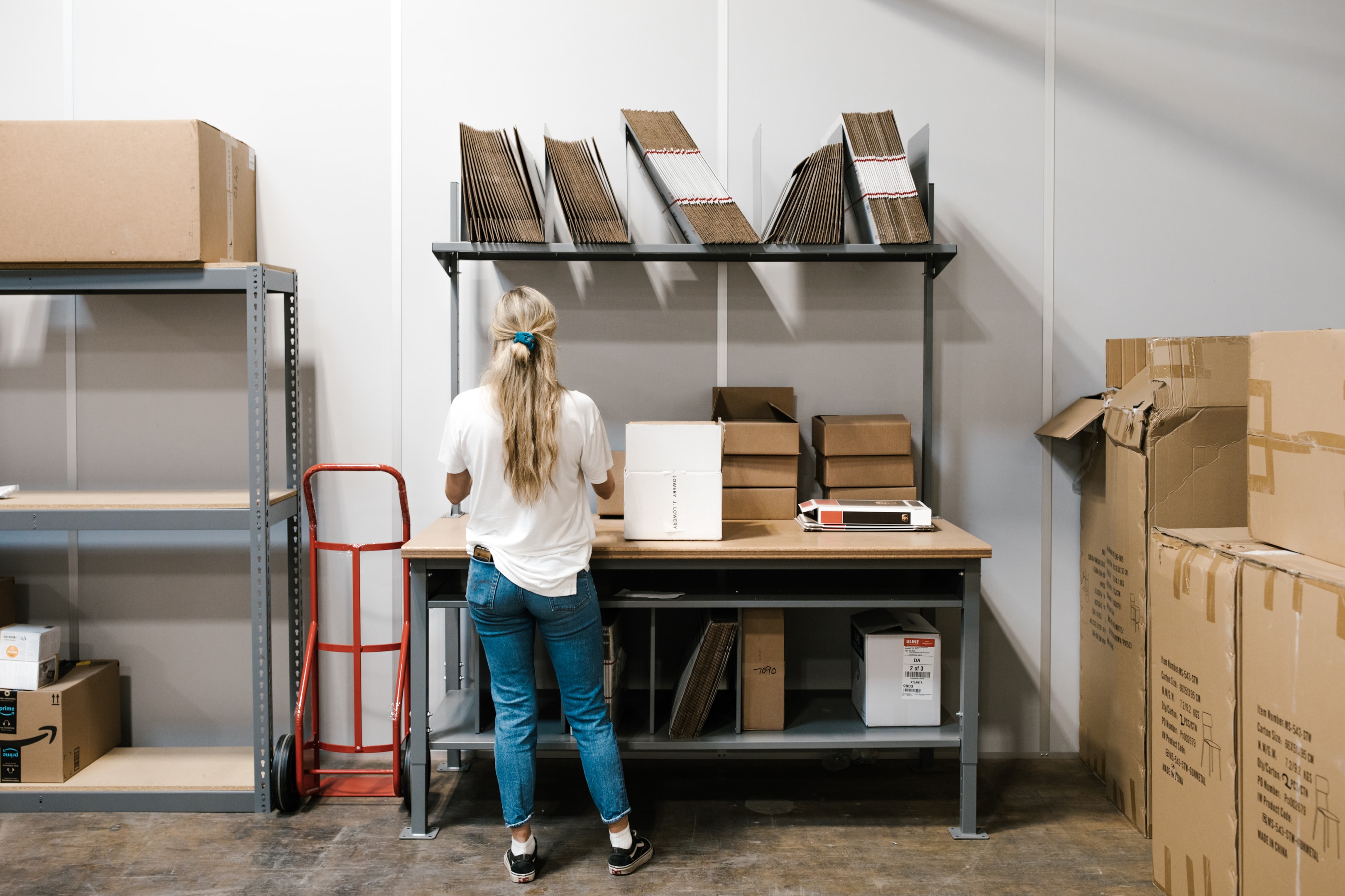 A woman at a fully-equipped packing station packing an order for her online business.