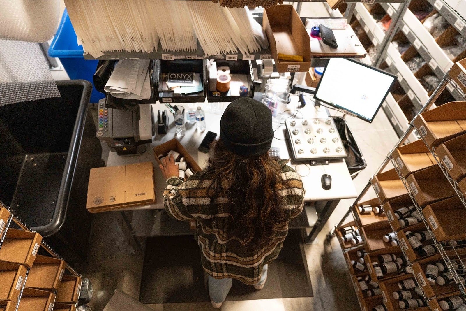 Business owner stands in a warehouse reviewing inventory as she reevaluates her fulfillment strategy against the new 2026 tariff updates.