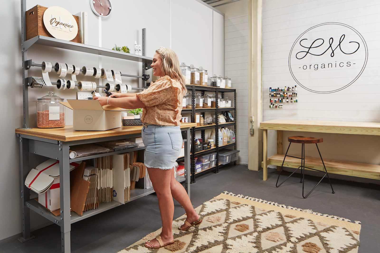 A small business owners packages a box for shipping in her small bay warehouse space.