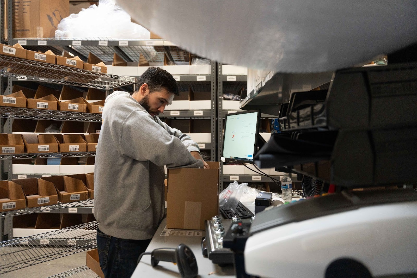 An entrepreneur works in the packing station as they decide how to set up a warehouse workflow for their business.
