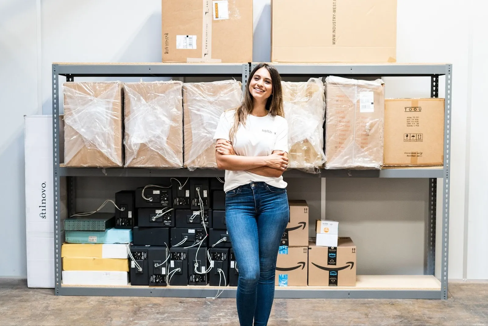 An ecommerce owner stands in front of her inventory after clarifying how to set up a warehouse for her company.