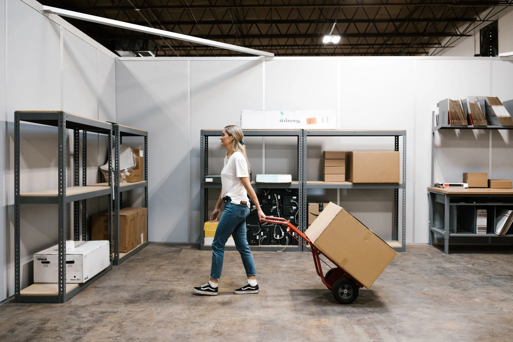 An ecommerce owner demonstrates how to use a pully dolly as she plans out the how to manage a warehouse team better.